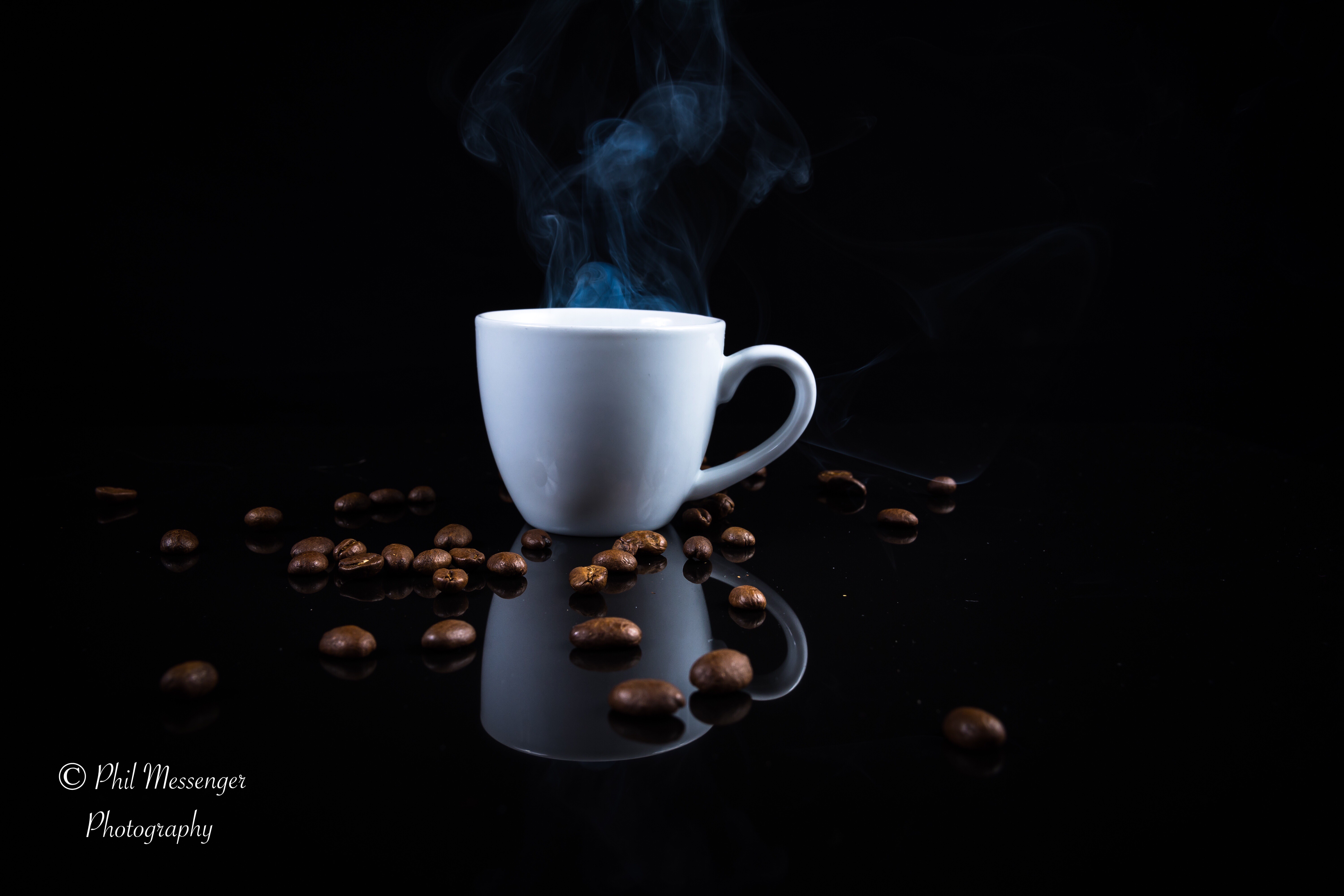Hot Coffee and a scattering of beans on a black background 