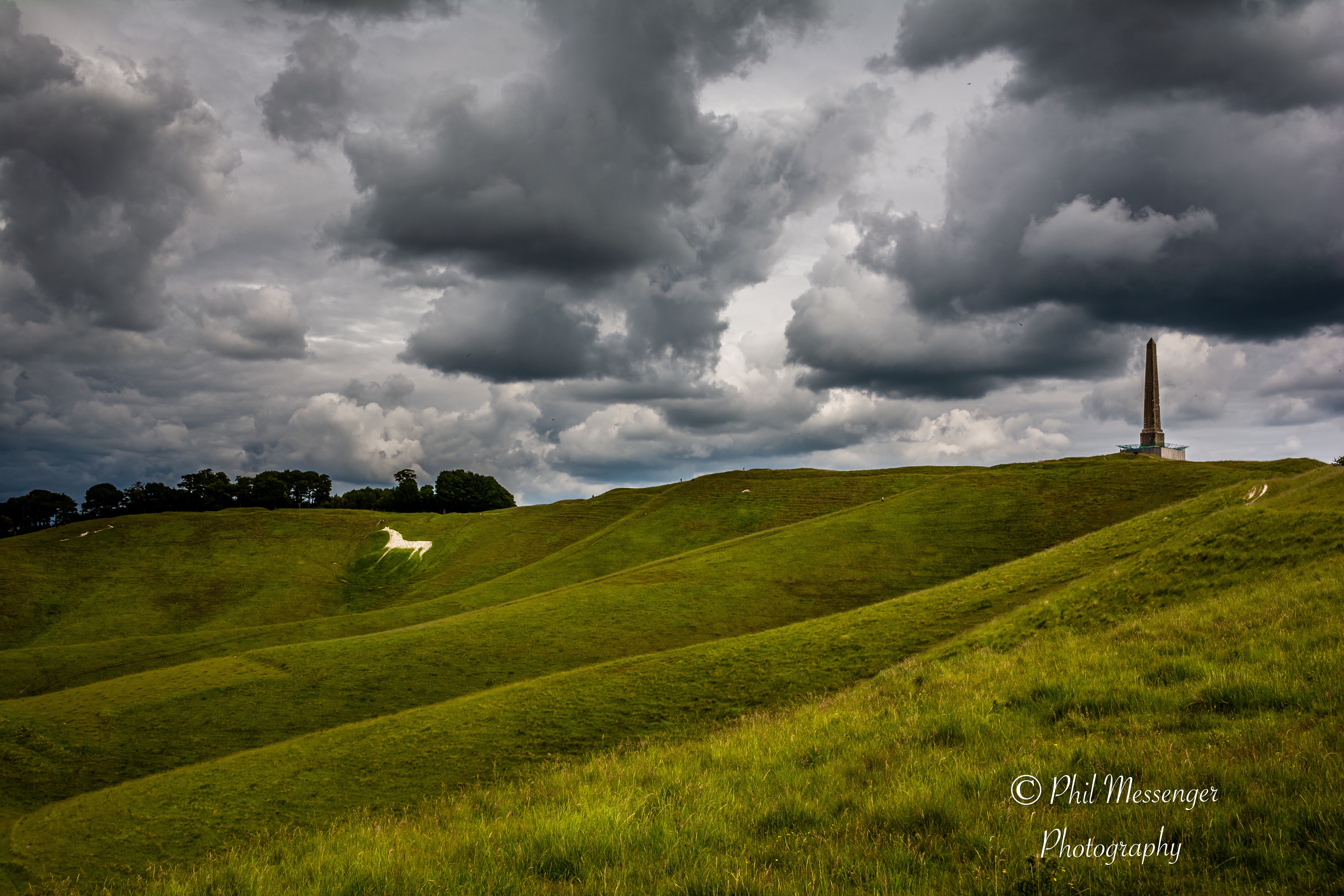 Cherhill monument and white horse in Wiltshire, England under cloudy skies.