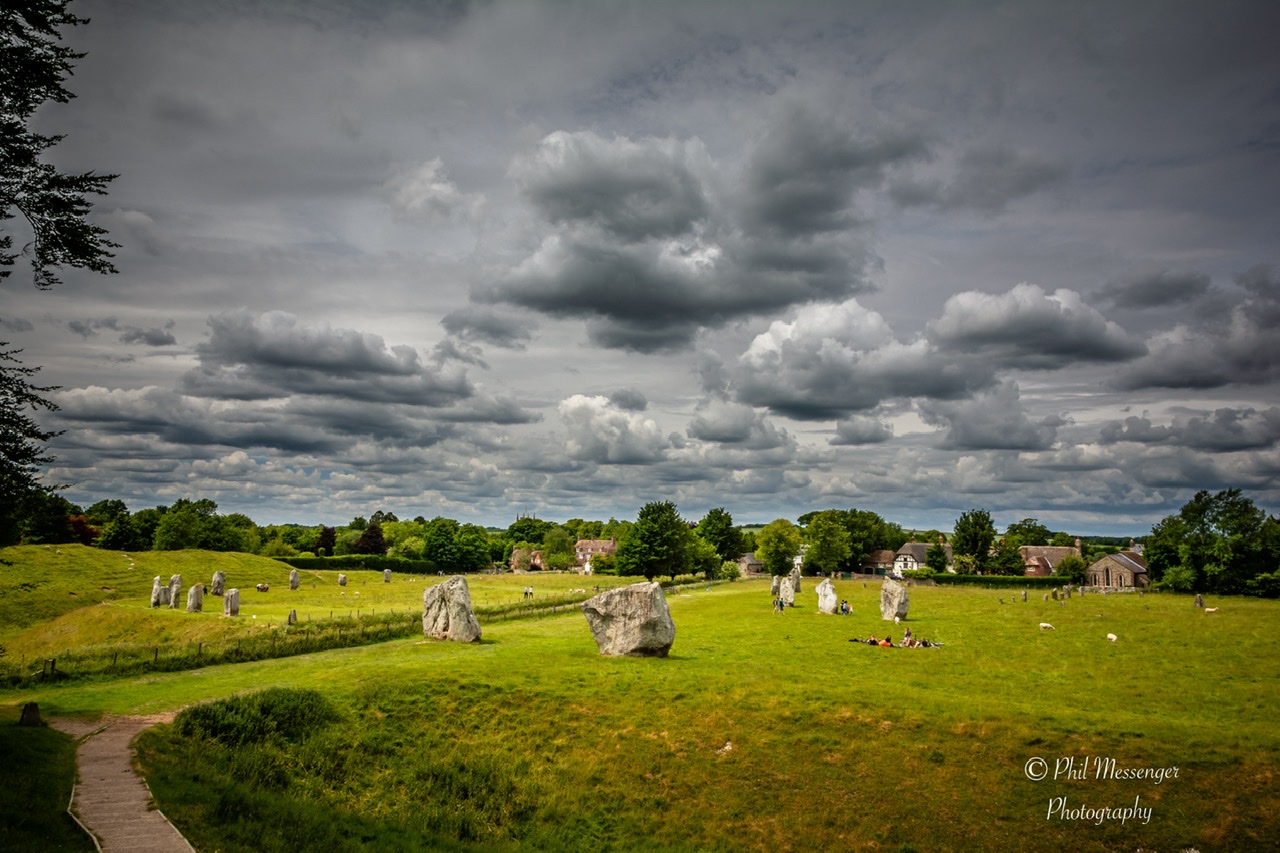 Avebury stone circle in Wiltshire, England under a cloudy sky.