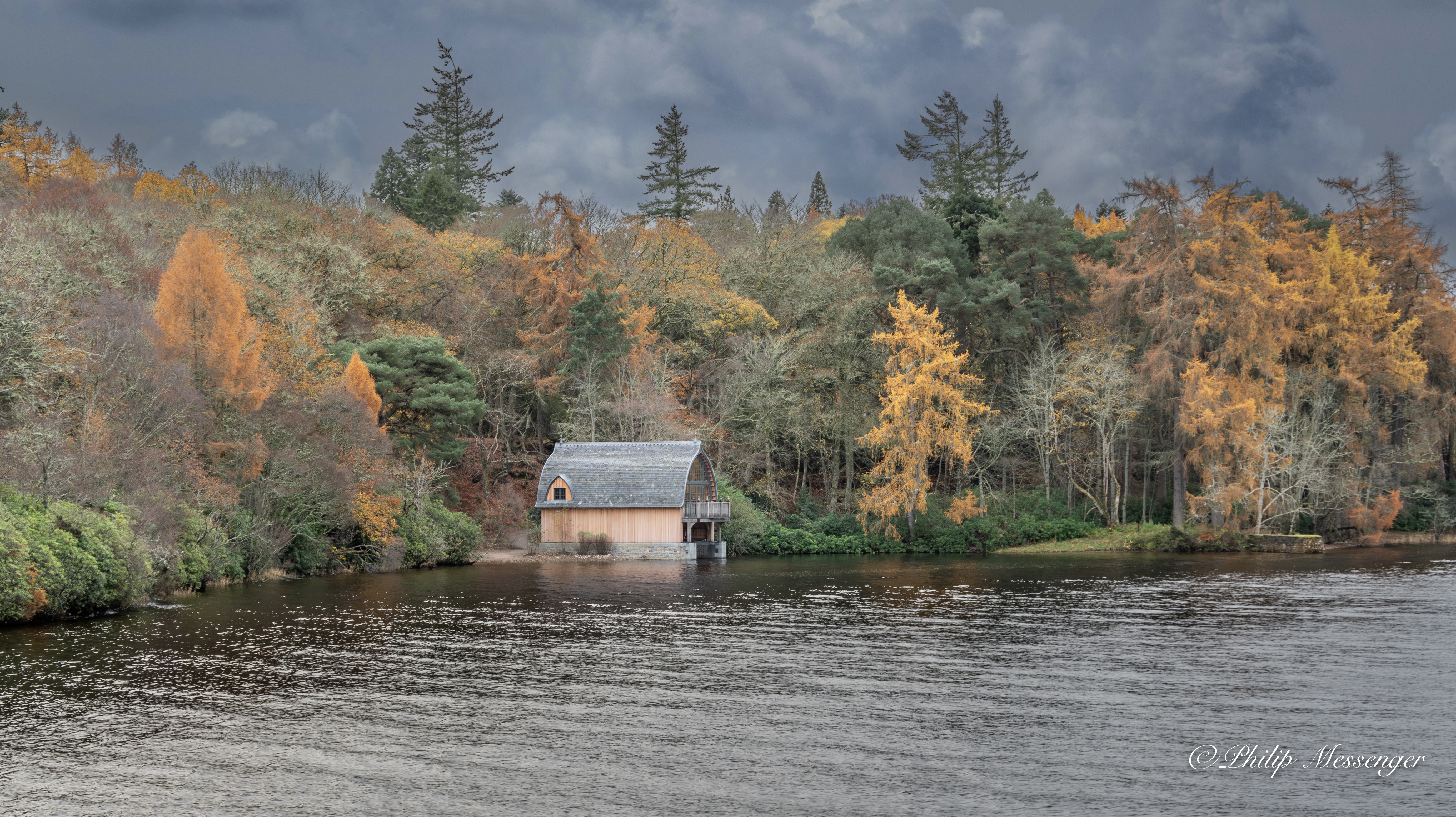 A boat house surrounded by accents of Autumn colours on the shore of Loch Ness Scotland.